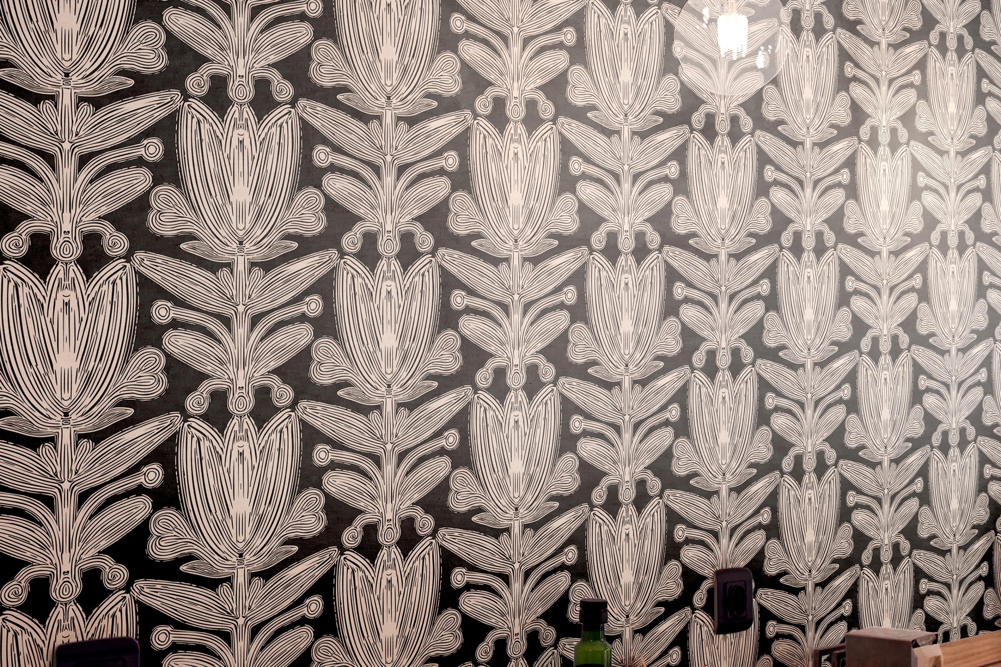 black and ivory botanical wallpaper above wood restaurant counter with pendant lights