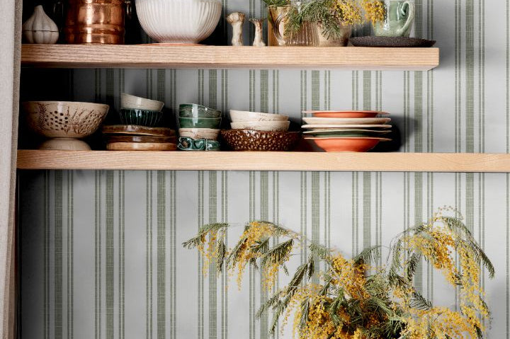 Sage Lineage wallpaper in kitchen with green and white stripes behind open shelving and ceramics
