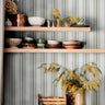 Sage Lineage wallpaper in kitchen with green and white stripes behind open shelving and ceramics