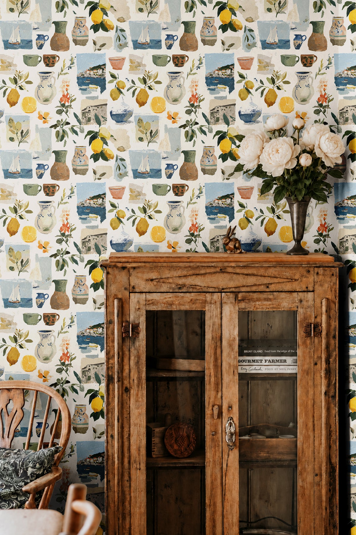 Sorella Coast 3143 Italian coastal wallpaper with watercolor lemons, Mediterranean pottery, sailboats and seaside scenes styled with a vintage wood cabinet