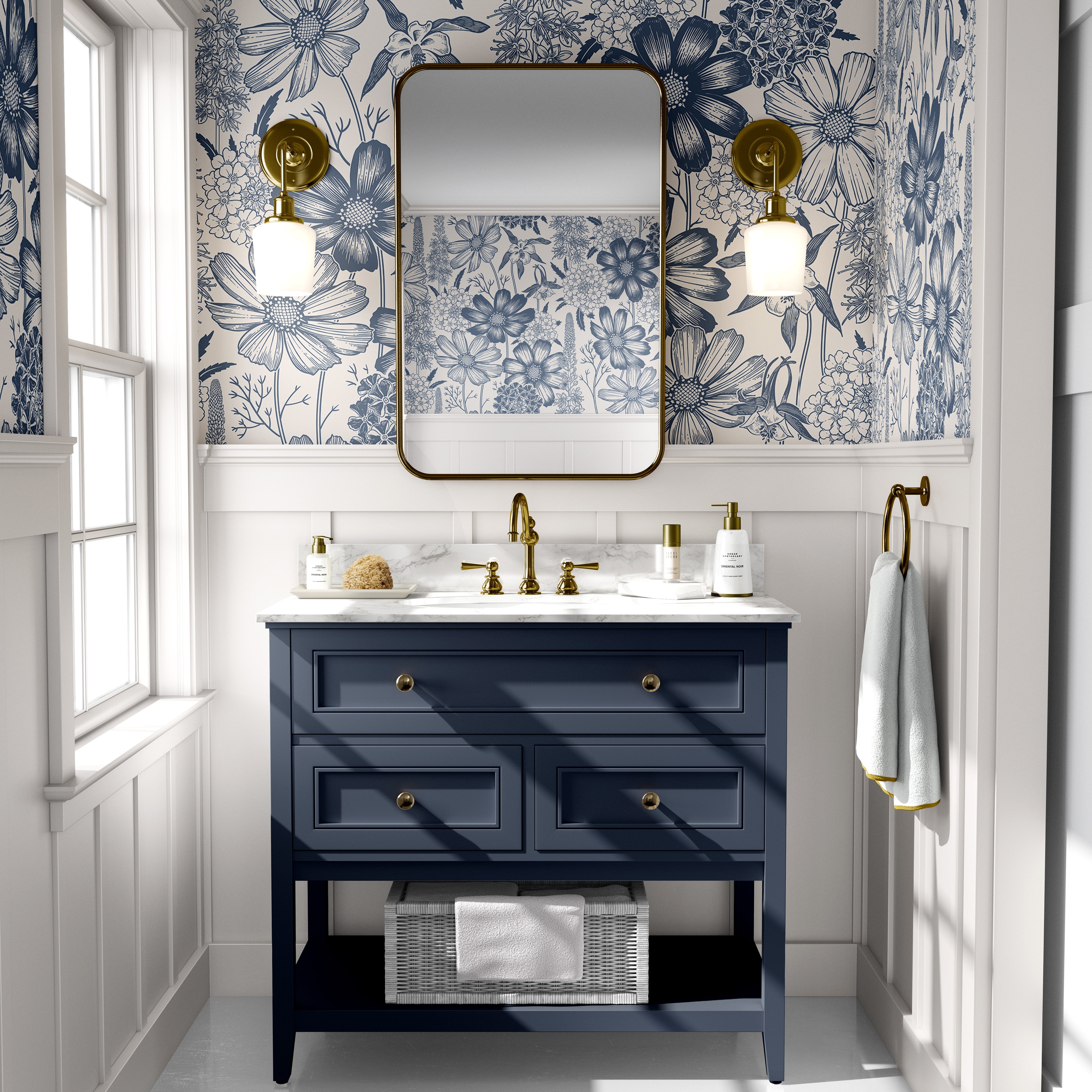 Blue floral toile wallpaper styled in a bright bathroom with a navy vanity, brass fixtures, and marble countertop.
