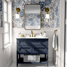 Blue floral toile wallpaper styled in a bright bathroom with a navy vanity, brass fixtures, and marble countertop.