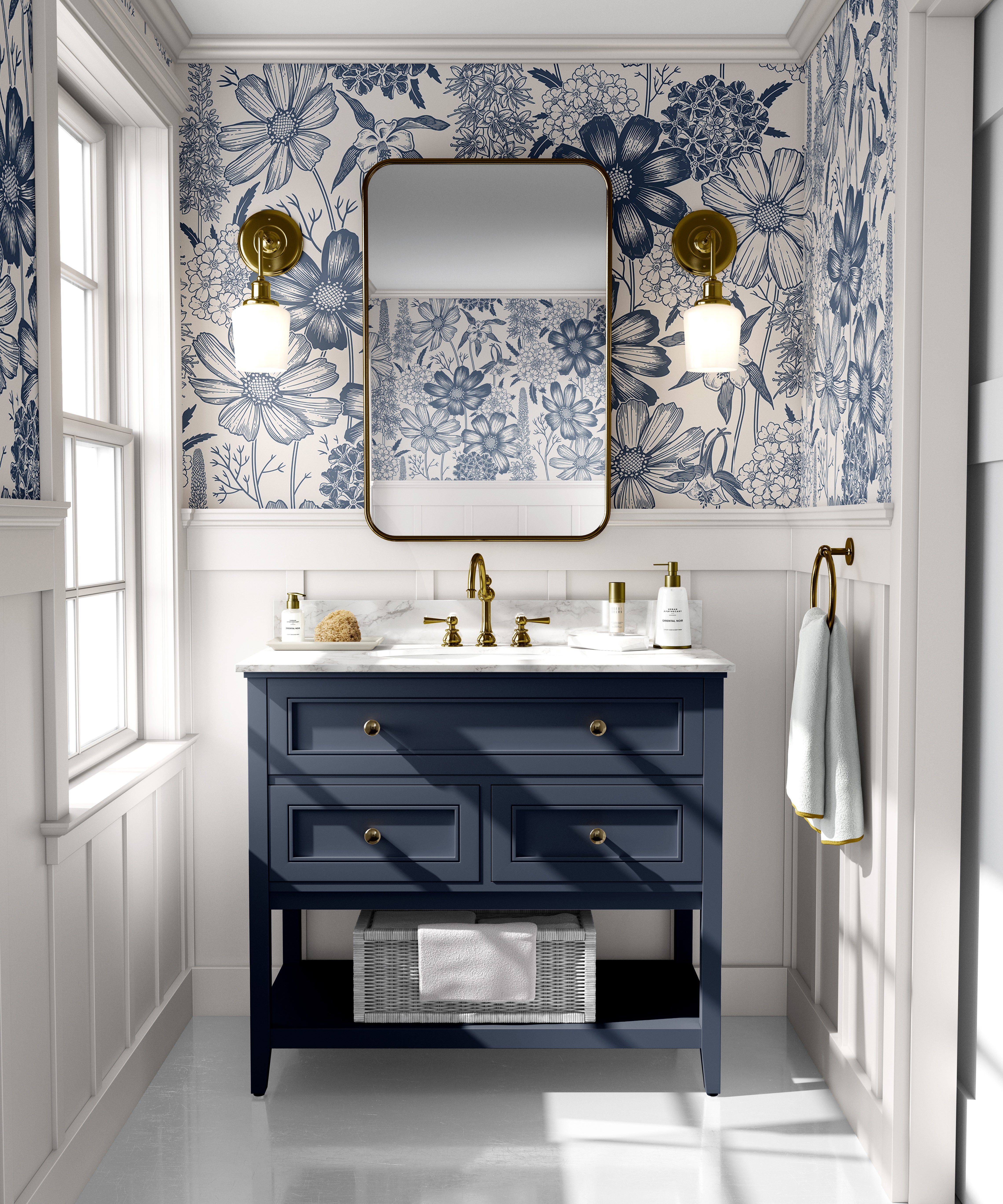 Blue floral toile wallpaper styled in a bright bathroom with a navy vanity, brass fixtures, and marble countertop.