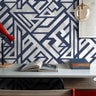 varsity ink 1263 navy geometric wallpaper behind a simple bed with gray bedding and white storage