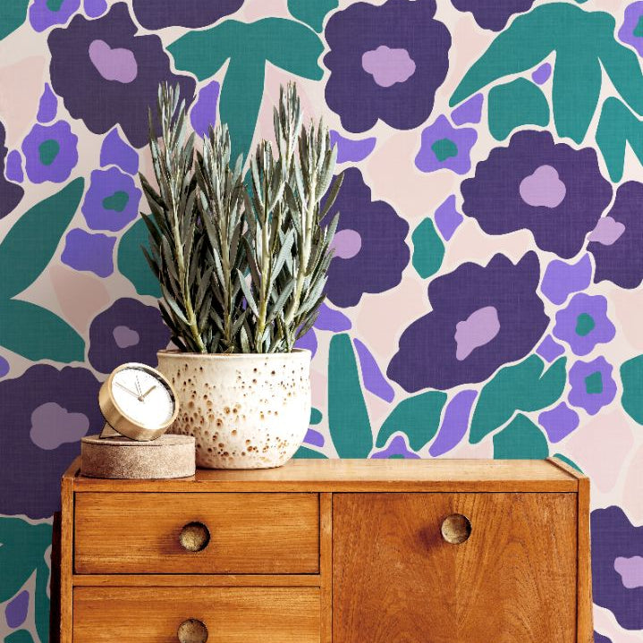Wood sideboard and greenery complementing Violetta Bloom Wallpaper’s bold violet and teal floral pattern.