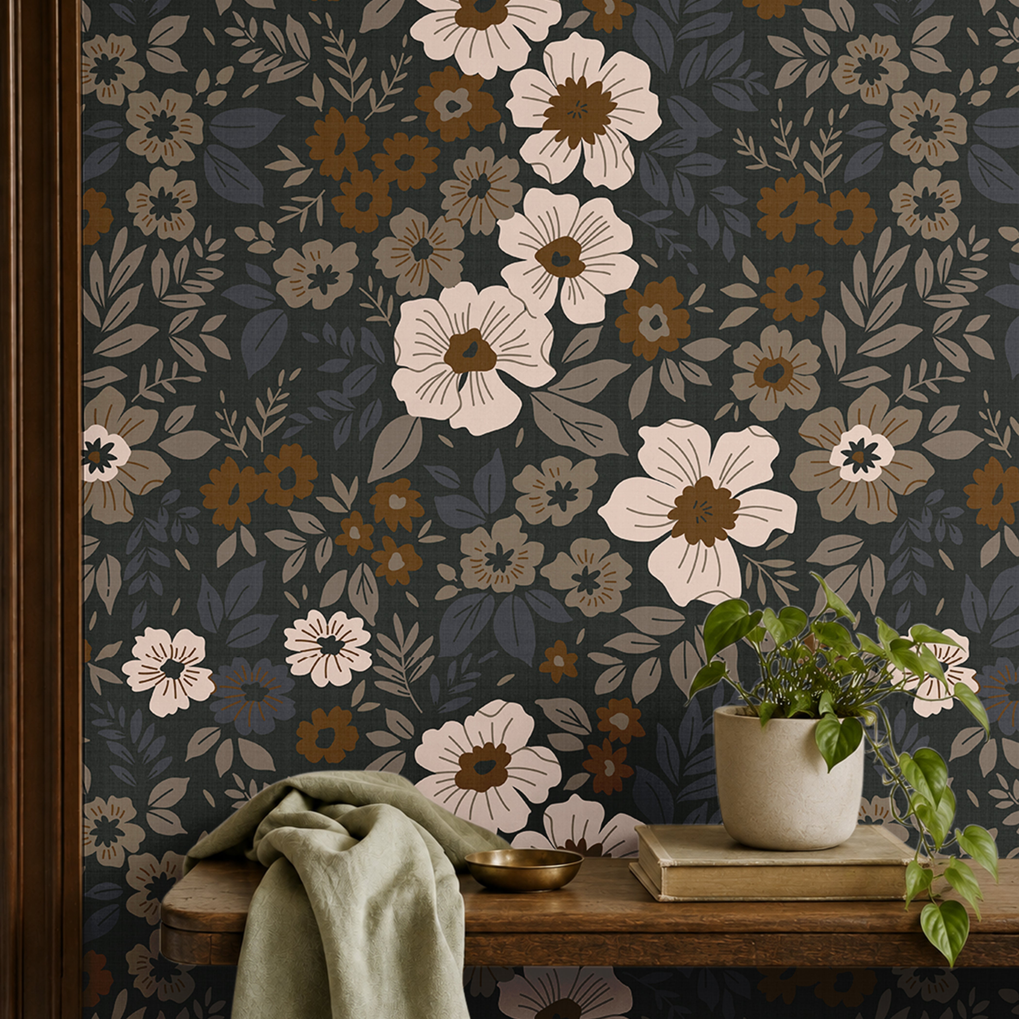 dark floral wallpaper with cream and amber flowers behind a wood bench with sage fabric and a potted plant
