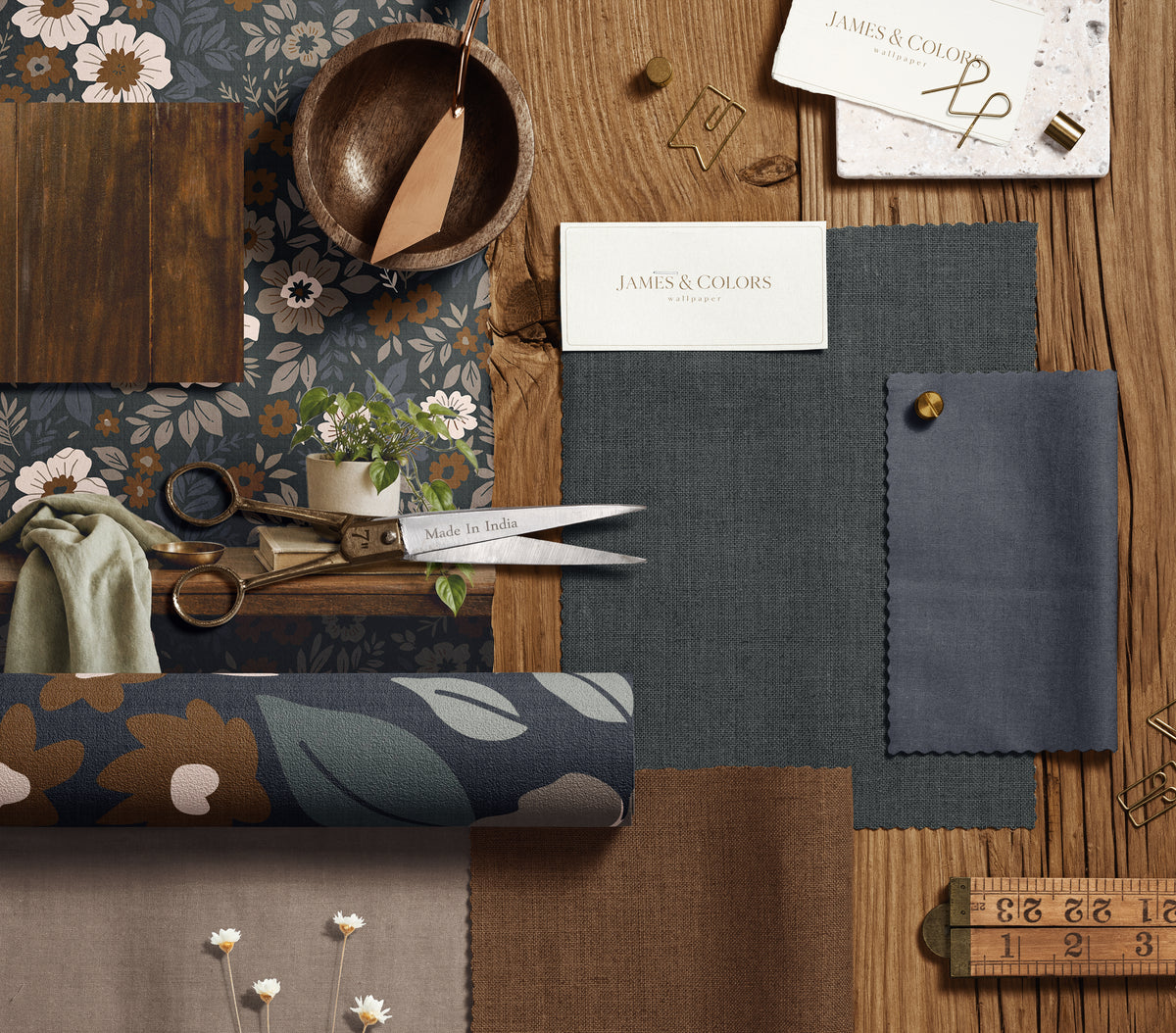dark floral wallpaper mood board with wood brass scissors and slate blue and brown fabric swatches
