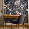 plum floral wallpaper behind plum chair and warm wood office desk 
