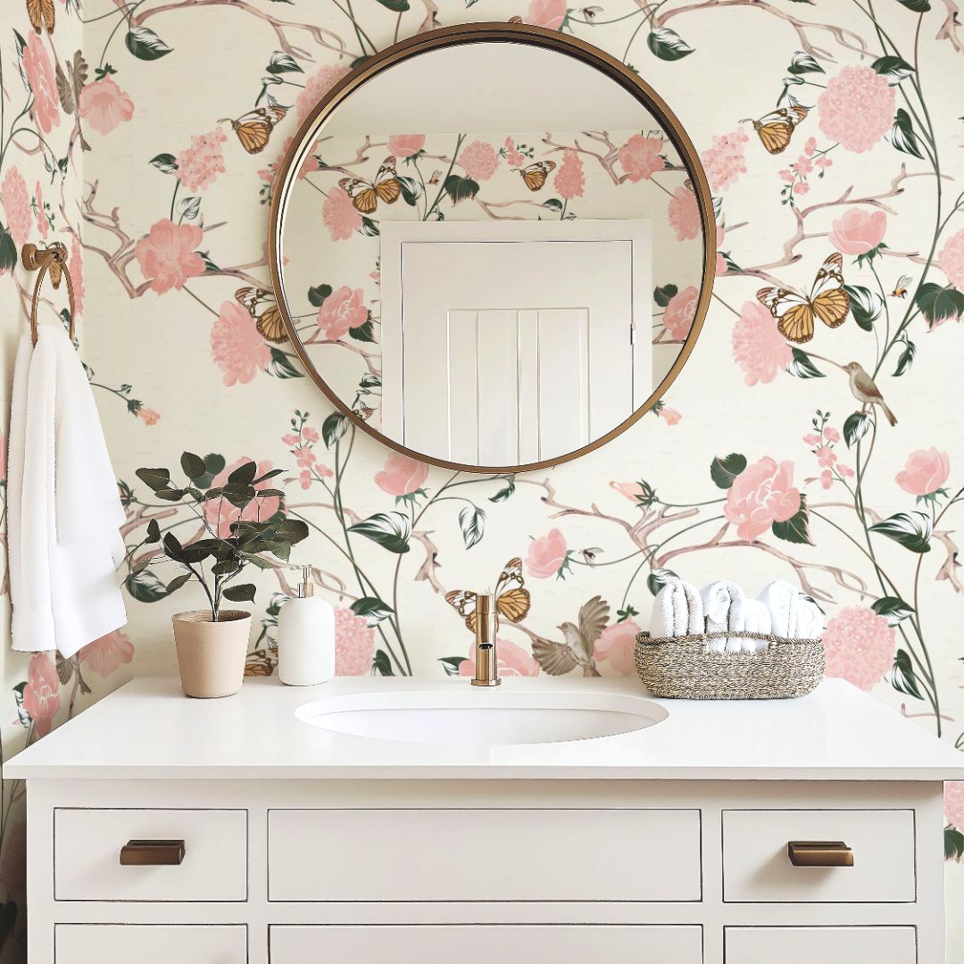 bathroom with blush floral wallpaper, butterflies and songbirds, round brass mirror
