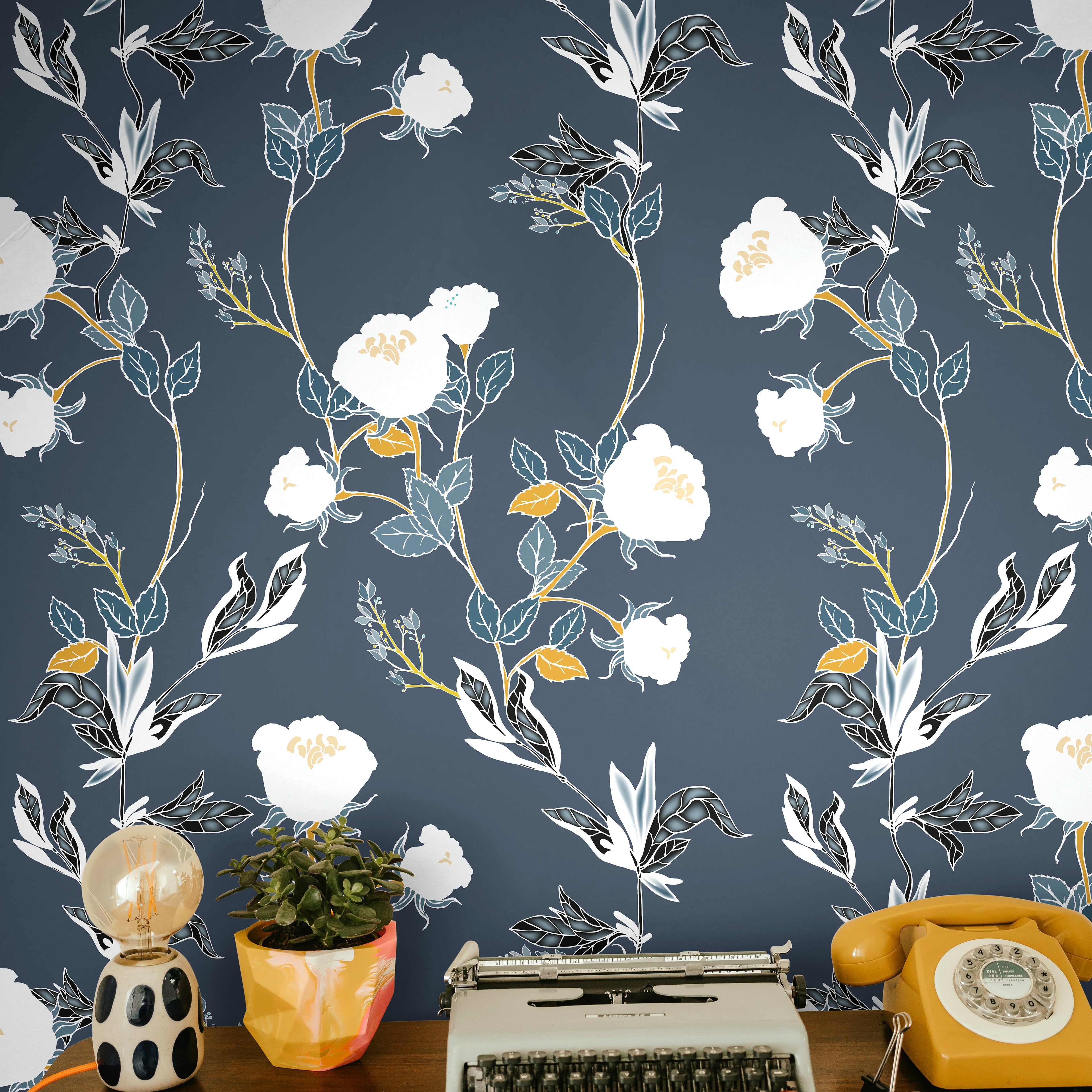 white florals with green and orange stems on lighter navy background behind eclectic desk interior