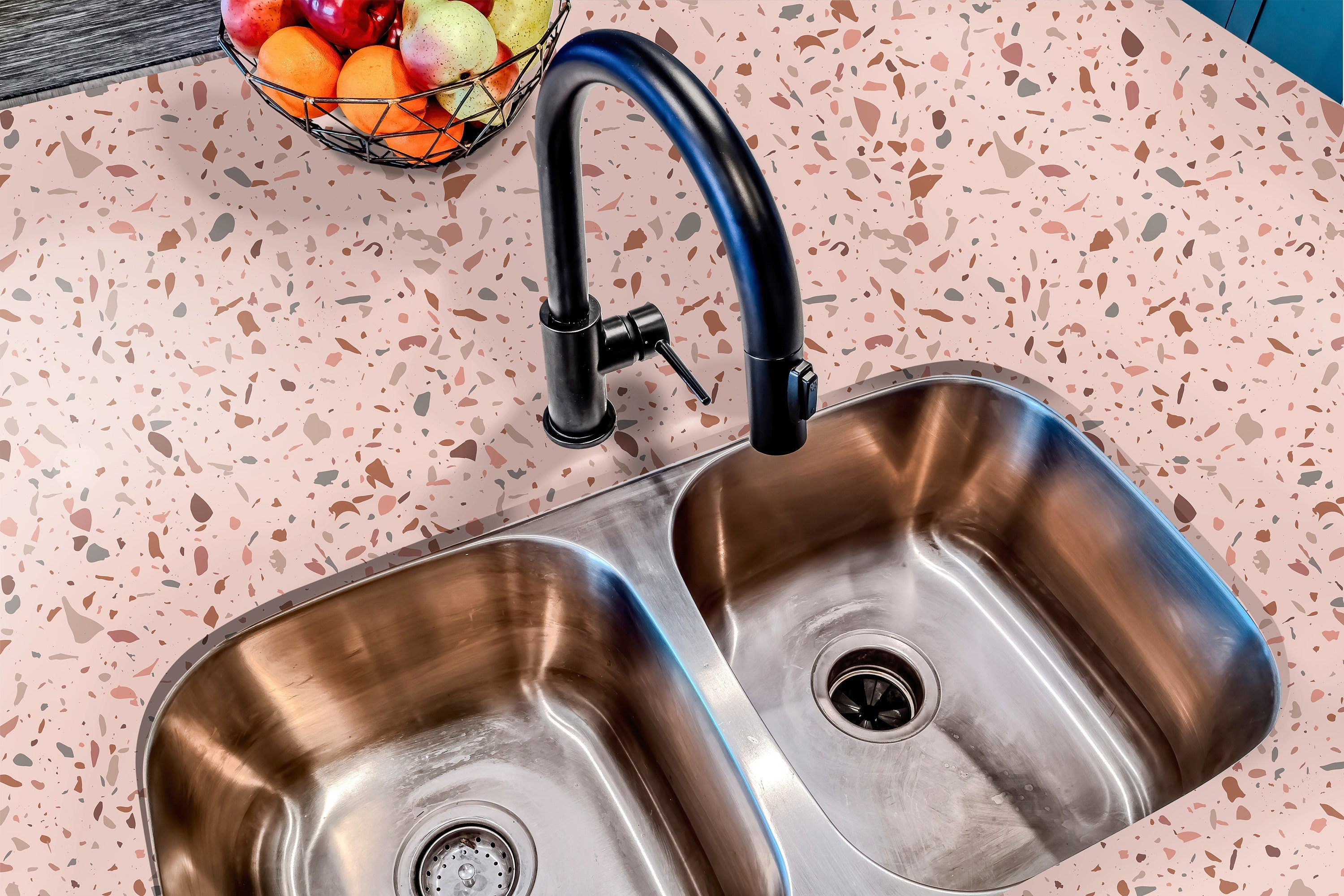 Countertop 20: A modern kitchen countertop covered in a blush pink terrazzo-patterned film with warm brown, terracotta, and neutral speckles, creating a soft and stylish aesthetic.
