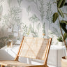 Wallpaper 583a: Minimalist room with green botanical line art wallpaper on a white background, featuring hand-drawn plants and leaves, styled with a woven chair, natural light, and organic textures.
