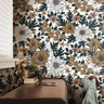 Wallpaper 786: Wallpaper featuring large hand-drawn florals in golden mustard, mauve, cream, and sage green on a soft beige background, styled behind a wooden desk with vintage books, plants, and a denim jacket.