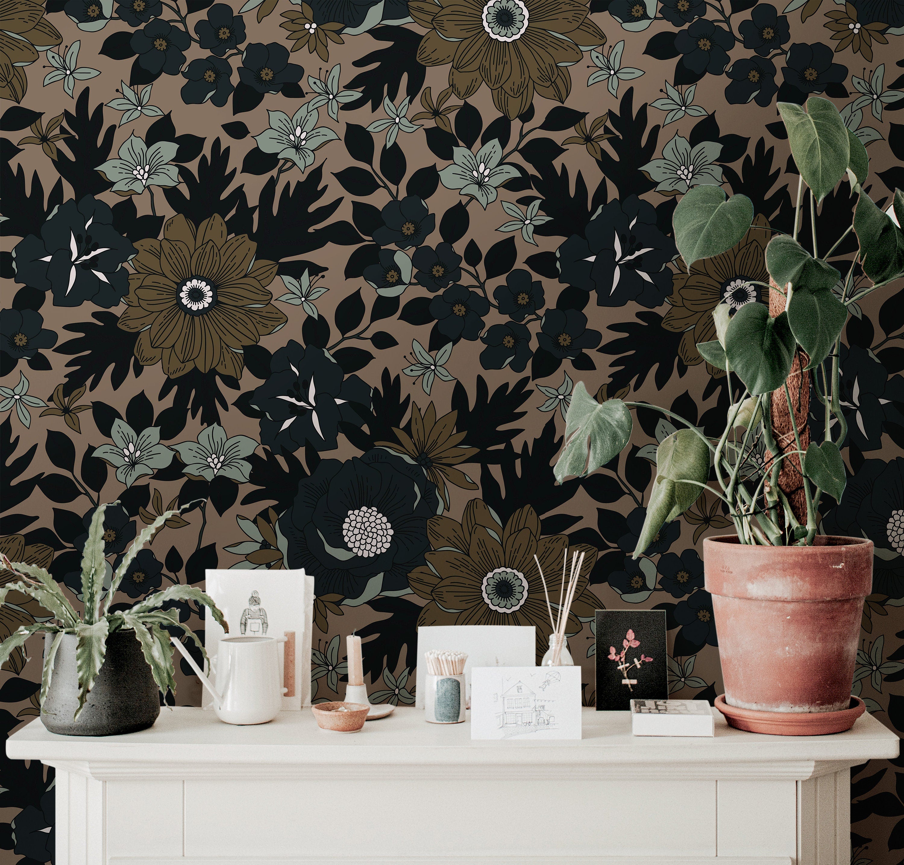 Wallpaper 919: Wallpaper featuring oversized black and olive floral motifs with pale green accents on a rich taupe background, styled with a cream console, terracotta potted plant, and earthy tabletop decor.