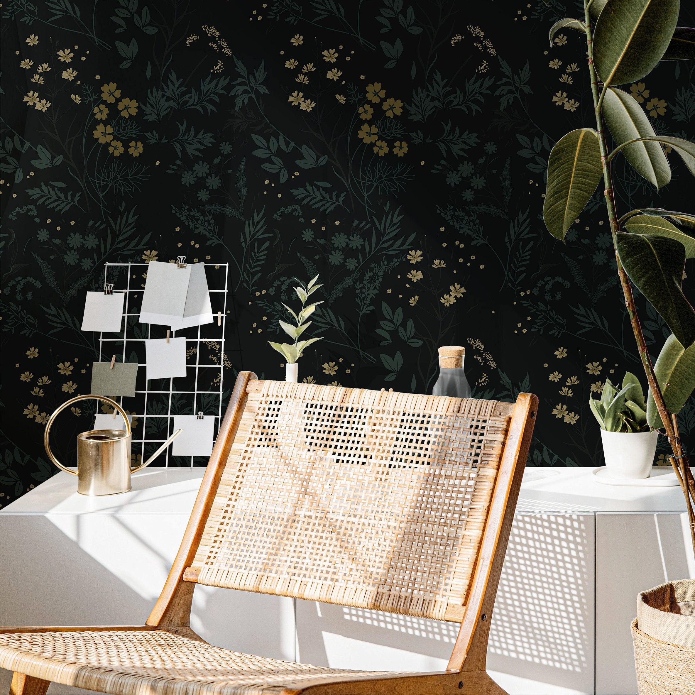 Wallpaper 863: Dark floral wallpaper featuring delicate yellow and green botanicals on a deep black background, styled with a woven lounge chair, modern decor, and indoor plants in natural light.