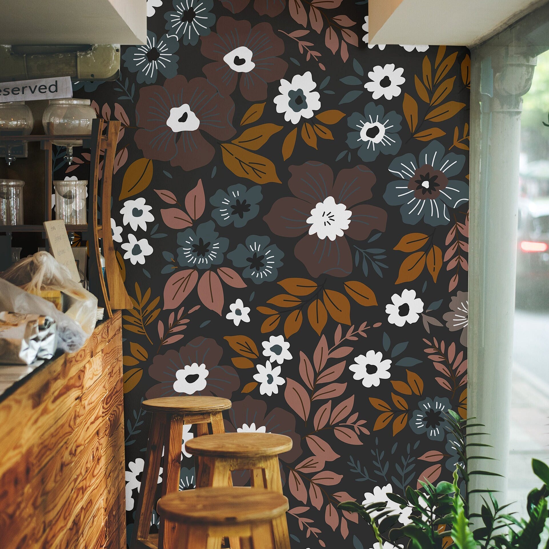 Wallpaper 1060a: Retro floral wallpaper with white, amber, rust, and dusty blue flowers against a dark background in a cozy café interior.